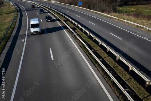 Fototapeta Naklejka Na Ścianę i Meble -  A white minivan and three cars are going down the highway.
