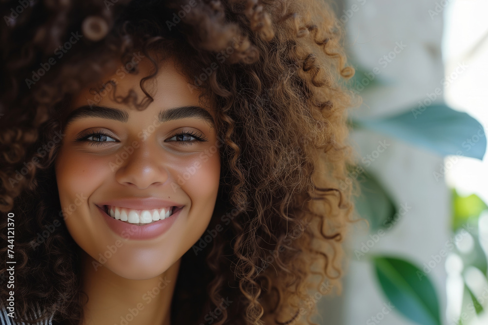 Radiant woman with voluminous curly hair and a bright smile, against a blurred natural background. Radiant woman with voluminous curly hair and a bright smile, against a blurred natural background.