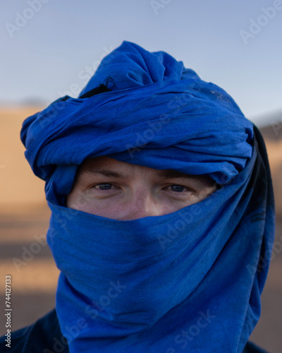 person wearing a blue head veil in the desert of Morocco