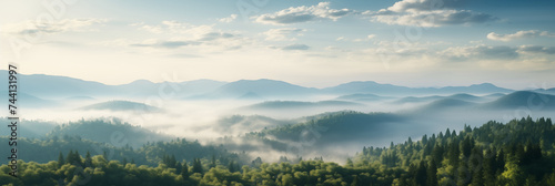 A panoramic view of a mountain range at dawn. Mist weaves through the valleys partially obscures the forested lower slopes. The rising sun illuminates the scene © Alex Shi