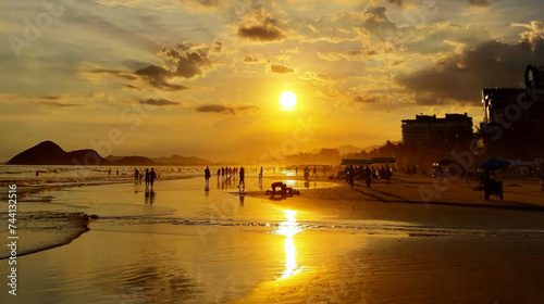 Sunset at the Beach showing people playing on the sand with waves on the left and buildings on the right 