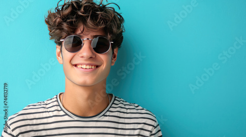 Portrait photograph of a young man smiling, dressed in stylish sunglasses and a striped t-shirt © yganko