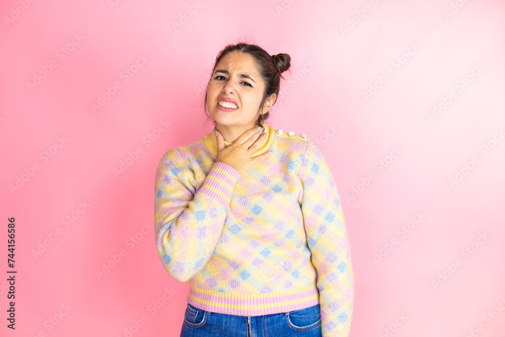 Young beautiful woman wearing casual sweater over isolated yellow background touching painful neck, sore throat for flu, clod and infection Young beautiful woman wearing casual sweater over isolated yellow background touching painful neck, sore throat for flu, clod and infection