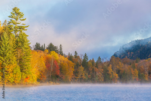 Lac-du-missionaire, Canada: Oct.10 2022: Morning fog on the lake of Lac-du-missionaire with colorful leaves in Quebec in a sunny autumn day