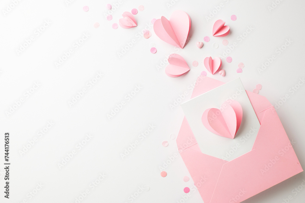 Heartfelt gestures: tokens of affection for her. Top view shot of paper hearts, confetti, and envelope on white background with space for personalized messages or advertisements