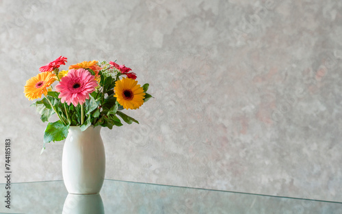 white vase with colorful flowers on a glass table, minimalist