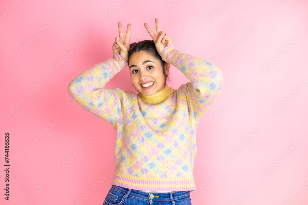 Young beautiful woman wearing casual sweater over isolated yellow background Posing funny and crazy with fingers on head as bunny ears, smiling cheerful Young beautiful woman wearing casual sweater over isolated yellow background Posing funny and crazy with fingers on head as bunny ears, smiling cheerful