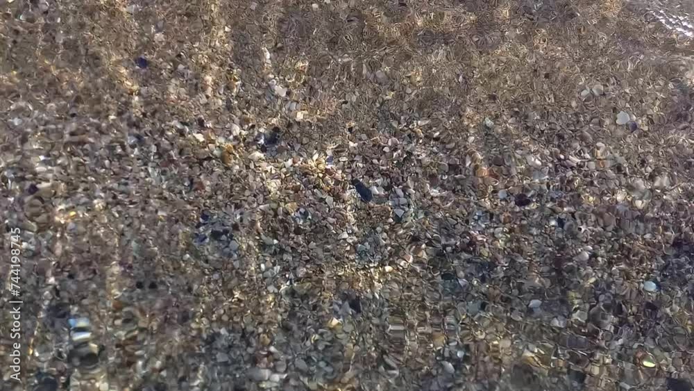 Seabed in shallow waters of Black Sea in Bulgaria. Small colored pebbles and shells are visible through clear, clean sea water. Natural background Seabed in shallow waters of Black Sea in Bulgaria. Small colored pebbles and shells are visible through clear, clean sea water. Natural background
