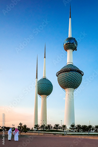 The Kuwait Towers in Kuwait City and two sheikhs from behind discussing and walking at sunset photo