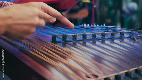 Musician plays on cymbalo - Ukrainian folk instrument. Male hands playing on dulcimer on the concert. Hammered dulcimer in slow motion photo