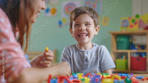 Child Development School. Professional woman language teacher exercising with preschooler, happy little boy making word with colorful letters on table, free space 