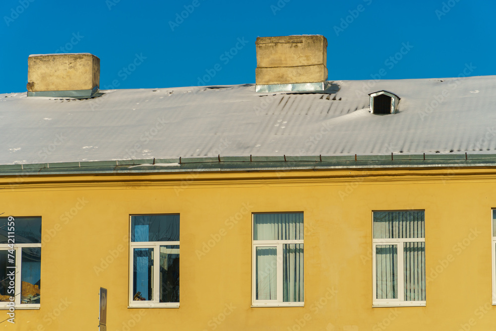 Snow and ice on the roofs of buildings. Icicles hang from the roofs of houses. The probability of the roof collapsing under the weight of snow. Snow and ice on the roofs of buildings. Icicles hang from the roofs of houses. The probability of the roof collapsing under the weight of snow.