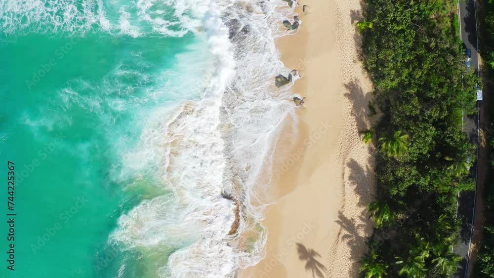 Bird's eye aerial shot of the Atlantic Ocean waves on a tropical sandy beach in Pinones, Puerto Rico