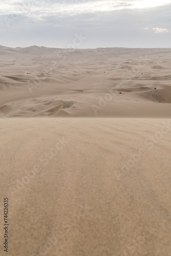 views of the desert that surrounds the town of Huacachina, from the top of the dunes that surround it, on a cloudy day. Portrait orientation