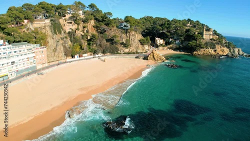 Sa Caleta beach in Lloret de Mar Castle on the rocks young tourist flying with Drone over the main beach, blue, turquoise water without people photo