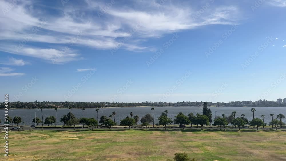 Riverside Drive in Perth, Western Australia with palm trees along the Swan River with wispy clouds above on a blue sky day Riverside Drive in Perth, Western Australia with palm trees along the Swan River with wispy clouds above on a blue sky day