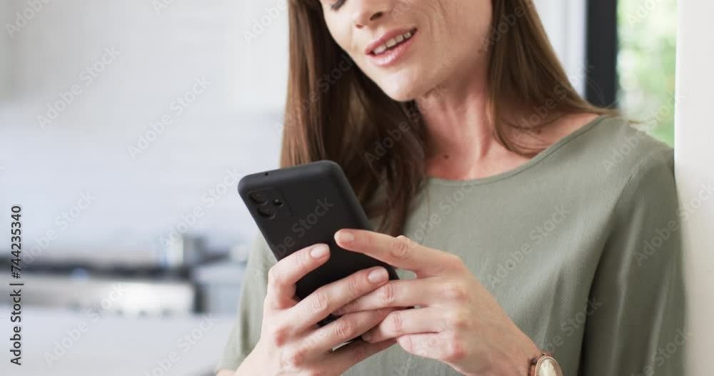 Middle-aged Caucasian woman texts on her smartphone at home Middle-aged Caucasian woman texts on her smartphone at home