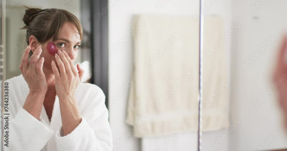 Middle-aged Caucasian woman applies skincare in a bathroom, with copy space Middle-aged Caucasian woman applies skincare in a bathroom, with copy space