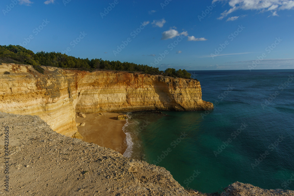Golden rock cliffs at the coastline of the Atlantic Ocean with beach Praia da Corredoura near the Cave of Benagil, Algarve, Portugal