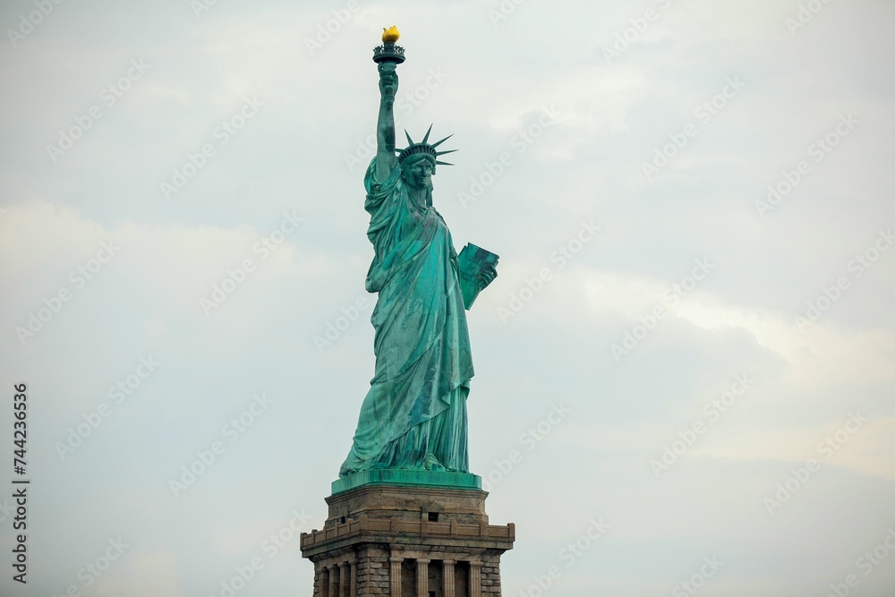 Fototapeta premium Side view of the iconic Statue of Liberty standing against a cloudy sky