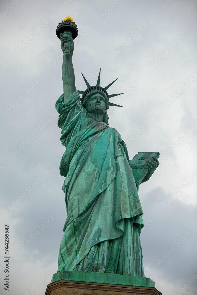 Fototapeta premium Low-angle view of the iconic Statue of Liberty standing against a cloudy sky