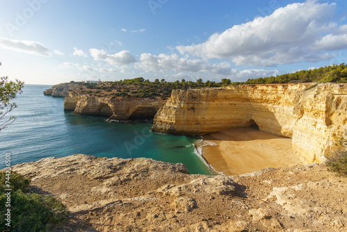 Golden rock cliffs at the coastline of the Atlantic Ocean with beach Praia da Corredoura near the Cave of Benagil, Algarve, Portugal photo