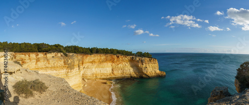 Panorama of golden rock cliffs at the coastline of the Atlantic Ocean with beach Praia da Corredoura near the Cave of Benagil, Algarve, Portugal