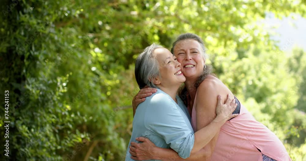 Senior Caucasian and Asian women share a joyful embrace outdoors Senior Caucasian and Asian women share a joyful embrace outdoors