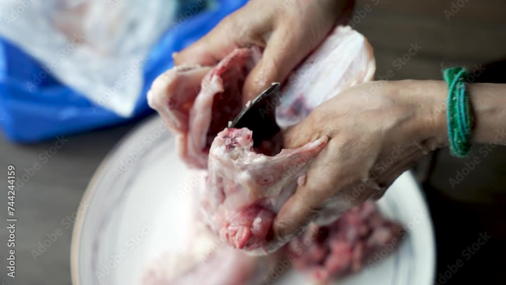 Close-up of hands cutting raw chicken with a traditional Aruvamanai cutter Close-up of hands cutting raw chicken with a traditional Aruvamanai cutter