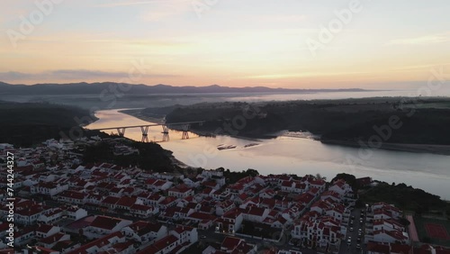 Sunrise View Of Road Bridge Over River Mira In The Town Of Vila Nova de Milfontes, Alentejo, Portugal. aerial pullback shot photo