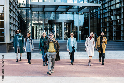 Successful diverse business group of people walking to the camera showing confidence over office building background. Leadership and partnership concept.