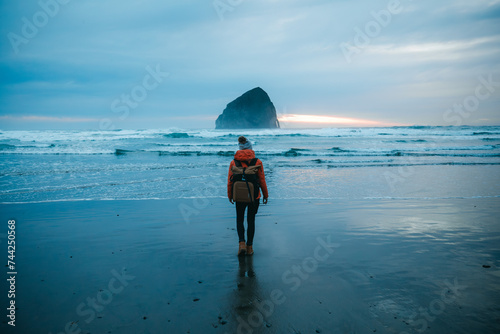 Young woman standing in front of Haystack Rock in Cape Kiwanda State Park. Pacific City  Oregon  USA.