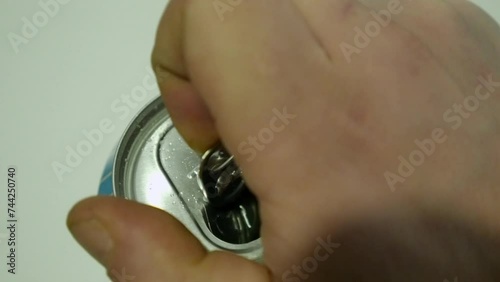 Closeup view: Male right hand opens pull tab on aluminum drink can
