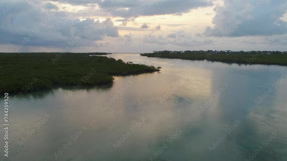 A low-flying drone shot over the clear blue water cutting through the unique mangrove environment during sunrise, near Islamorada of the Florida Keys, USA. A low-flying drone shot over the clear blue water cutting through the unique mangrove environment during sunrise, near Islamorada of the Florida Keys, USA.