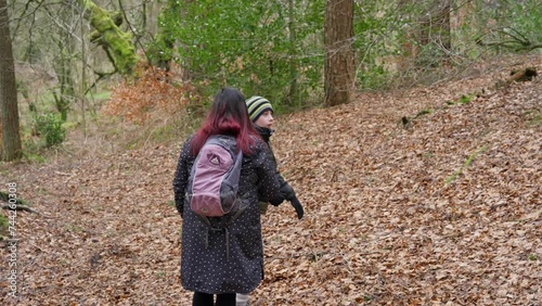 Young boy and his mother walking on a rural footpath on a day out in the forest woodlands. Countryside activity scene with moorlands winter scene