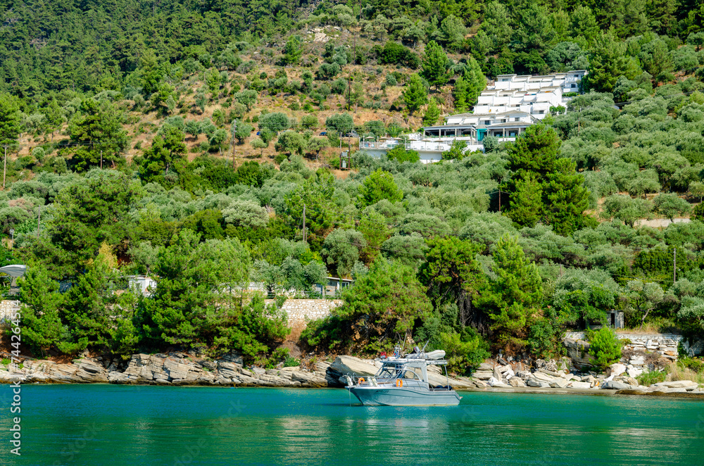 Boat on tranquil water near lush trees and house in Thassos, Greece