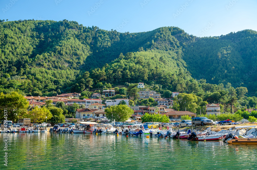 Small town harbor with boats on water in Thassos, Greece