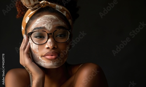 Vitibeautiful african american woman applying face mask on black background. skin care, beauty