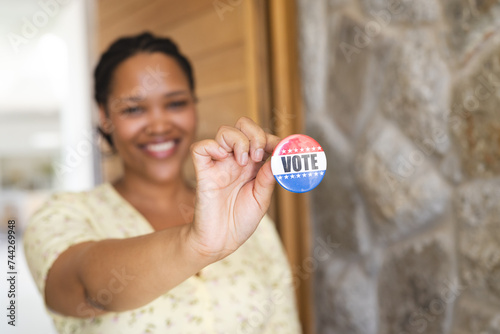 A young biracial woman shows off a 'Vote' badge proudly