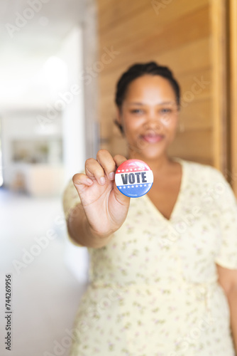 Young biracial woman holds a 'vote' badge, with copy space