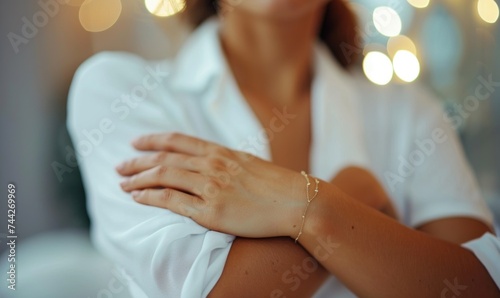 Close up of woman in white shirt with crossed arms, bokeh light