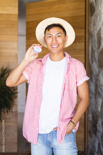 Young Asian man smiles holding a vote badge