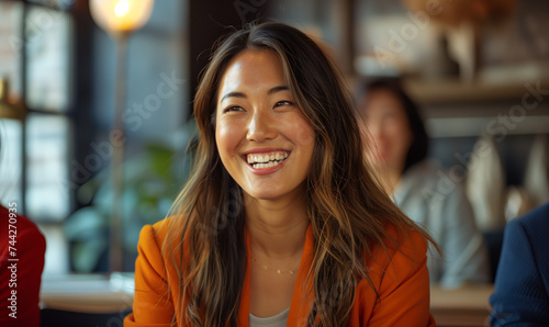 Portrait of a young asian woman smiling in the office. Happy young office colleagues collaborating and smiling in a casual meeting, setting business goals and team building photo