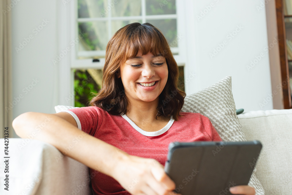 Young biracial woman smiles while using a tablet at home Young biracial woman smiles while using a tablet at home