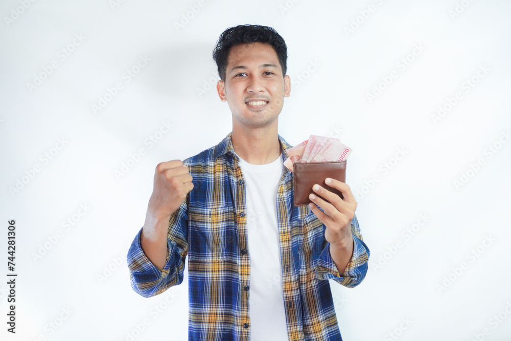 Adult Asian man showing excited face expression while holding his wallet full of money Adult Asian man showing excited face expression while holding his wallet full of money