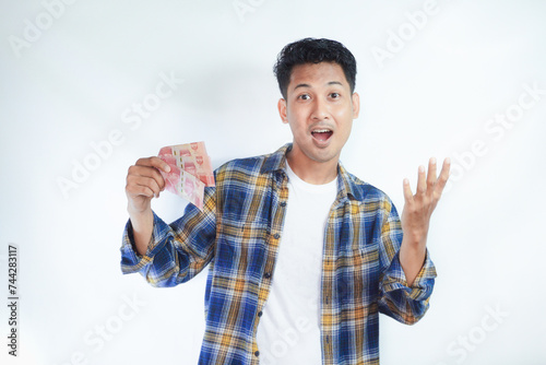 Adult Asian man clenched fist while holding Indonesia paper money and showing excited expression