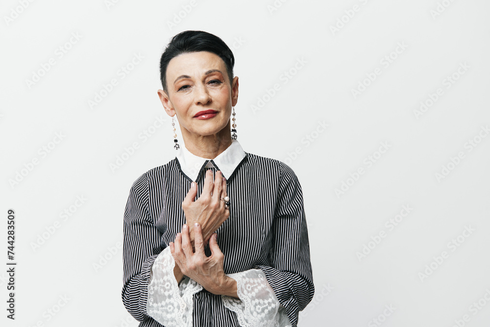 Confident woman in gray shirt and white collar standing with hands on hips in studio portrait