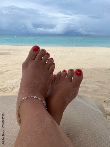 Woman’s feet in the sand facing the ocean