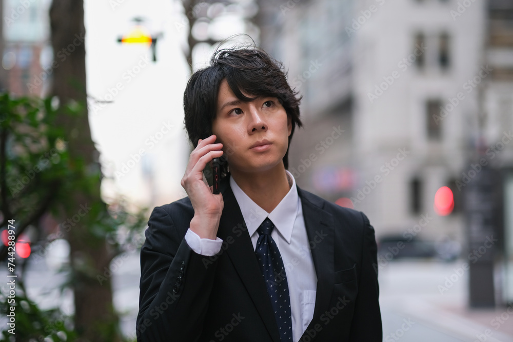 スマートフォンで電話をしながら歩いているビジネスマン スマートフォンで電話をしながら歩いているビジネスマン