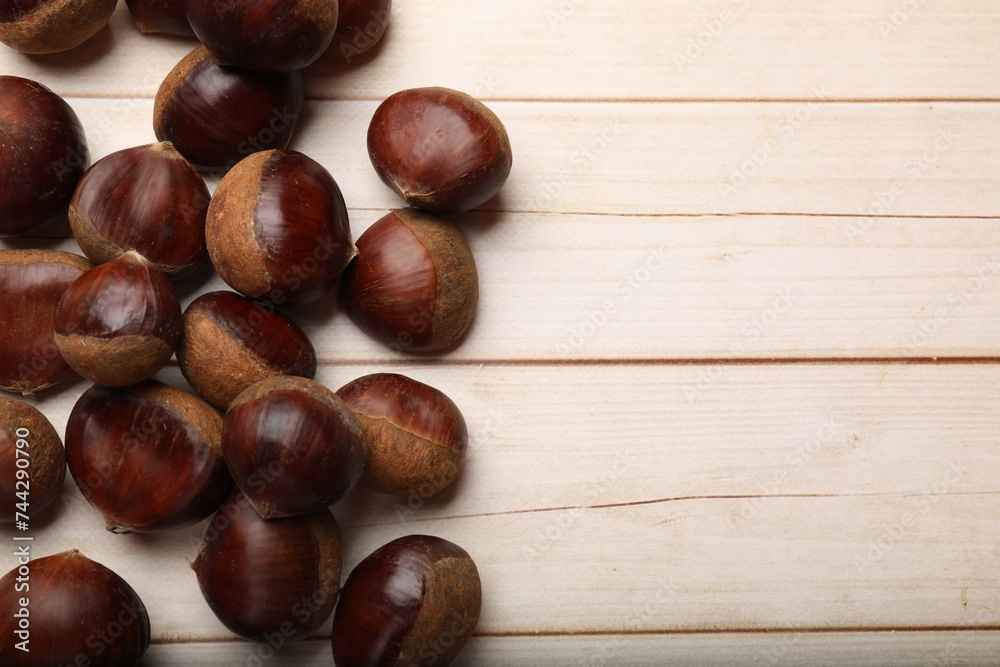 Sweet fresh edible chestnuts on light wooden table, top view. Space for text Sweet fresh edible chestnuts on light wooden table, top view. Space for text